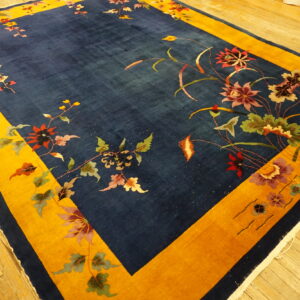 Plush indigo rug with a wide yellow frame border and scattered flowering vines on a wood floor.