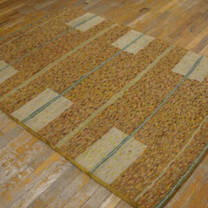A textured rug with multicolored gold and beige vertical stripes rests on distressed wood flooring.