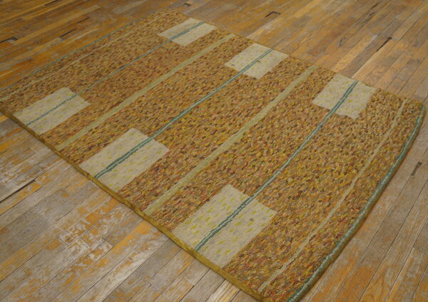A textured rug with multicolored gold and beige vertical stripes rests on distressed wood flooring.