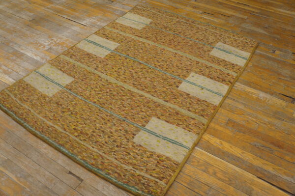 Textured gold and orange striped rug with horizontal cream rectangles lies on worn wood floors.