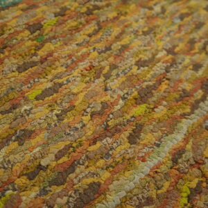 Highly textured close-up of a variegated rug with diagonal rows of gold, brown, rust, and green loops.