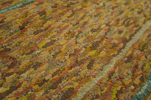 Highly textured close-up of a variegated rug with diagonal rows of gold, brown, rust, and green loops.