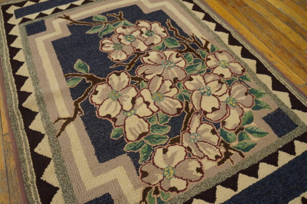 A high-texture rug featuring cream and gray flowers on navy blue, with zigzag borders on wood planks.