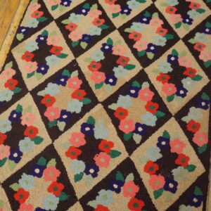 A dark brown and tan diamond rug with multicolored floral clusters lies on distressed wood floors.