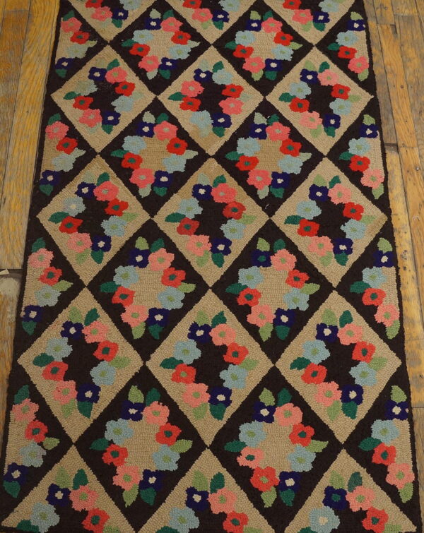 Tan and dark brown runner rug with multicolored floral designs inside a repeating diamond pattern on wood flooring.