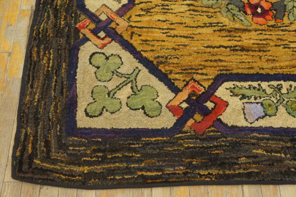 Chunky hooked rug corner detail with gold striped field, green leaves, red shapes, and dark mottled borders.