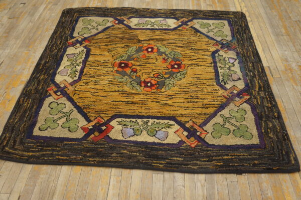 Mustard yellow hooked rug featuring a red floral wreath and green motifs within a dark brown textured border.