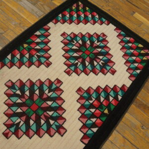 Runner rug with colorful geometric diamond designs and a black border rests on aged hardwood planks.