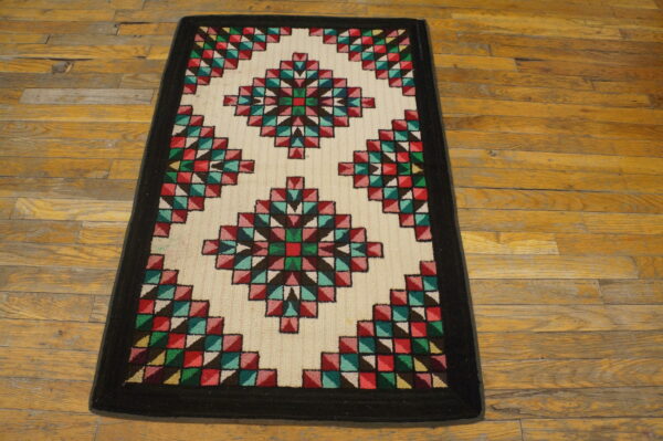 A colorful geometric runner rug featuring diamond patterns on a cream field, lying on distressed hardwood.