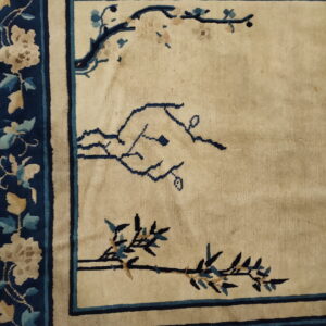 Navy blue border with tan flowers surrounds a beige field with sparse blue branch patterns.