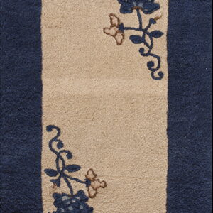Rug detail showing a tan central panel with navy floral motifs, bordered by dark blue pile.