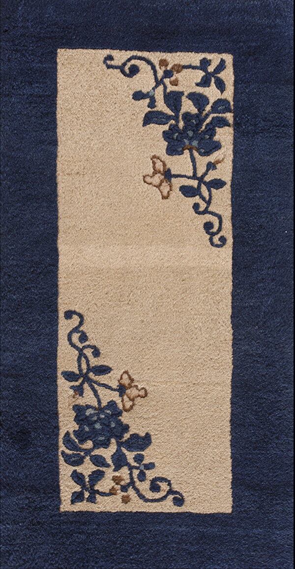 Rug detail showing a tan central panel with navy floral motifs, bordered by dark blue pile.