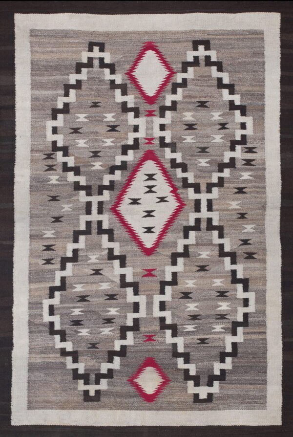 Gray flatweave rug with black, white, and red geometric stepped diamonds on a variegated field.