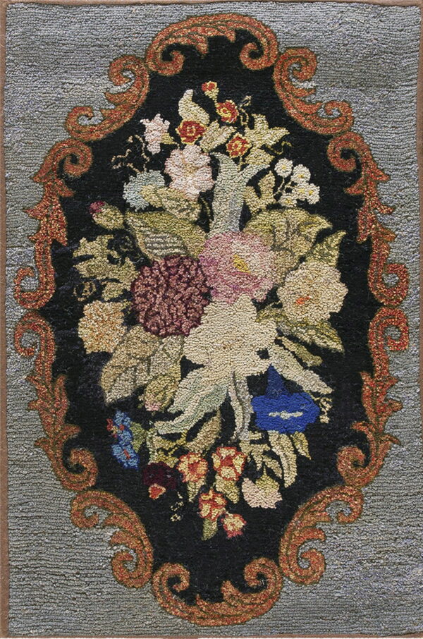 Textured loop pile rug featuring a detailed multicolored floral arrangement within an ornate reddish-orange oval border on a gray background.