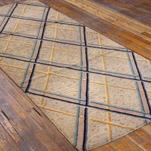 Beige textured rug with a navy, teal, and gold diamond grid on rustic hardwood floors.