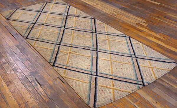 Beige textured rug with a navy, teal, and gold diamond grid on rustic hardwood floors.