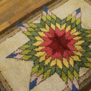 Multicolored high-pile rug featuring a vibrant star design in red, yellow, green, and blue on wood planks.