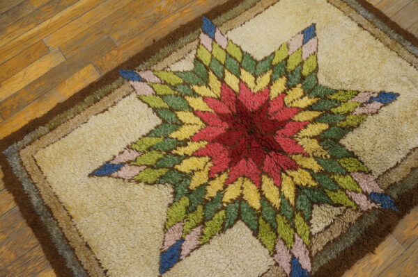 Multicolored high-pile rug featuring a vibrant star design in red, yellow, green, and blue on wood planks.