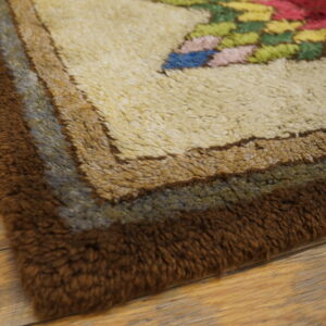 Shaggy rug border features bands of dark brown, blue-gray, and beige next to a multicolored floral pattern on wood flooring.