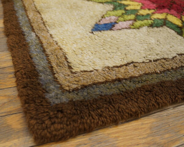 Shaggy rug border features bands of dark brown, blue-gray, and beige next to a multicolored floral pattern on wood flooring.