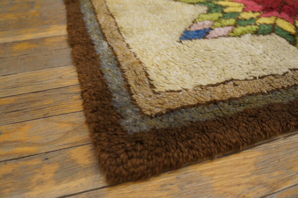 High-pile rug corner showing brown borders, cream field, and multicolor floral motifs on distressed wood.