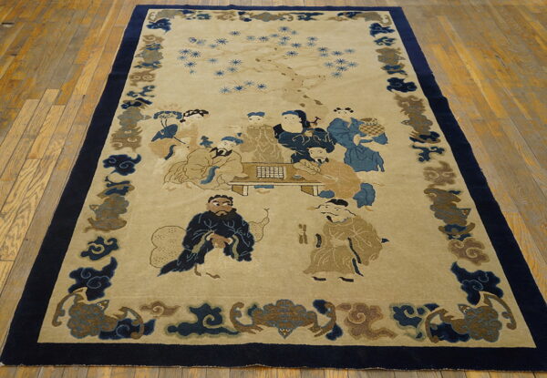 Light beige rug with blue and tan figures, surrounded by a dark navy border on wood flooring.