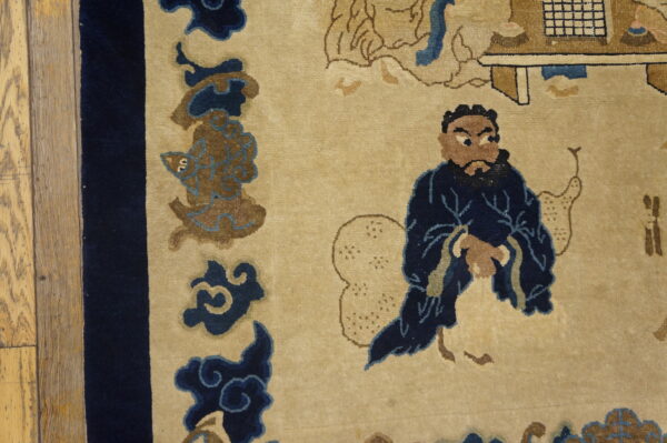 Tan rug detail showing a bearded man in a navy robe next to a dark blue border and wood floor.
