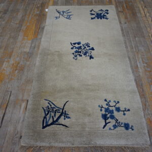 Light beige high-pile runner rug with scattered blue botanical designs rests on distressed wood flooring.