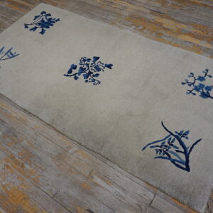A light gray rug featuring five scattered blue botanical designs rests on distressed wood floors.