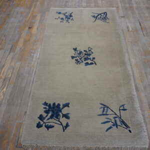 Neutral runner rug with indigo floral motifs displayed on aged, light brown wood planks.