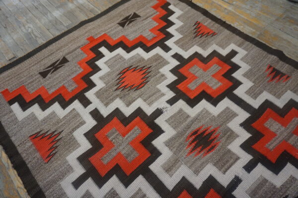 Flatweave rug with bright orange, gray, white, and brown geometric patterns on rustic wood floor.