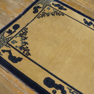 Gold rug with navy border featuring key patterns and abstract motifs on worn hardwood flooring.