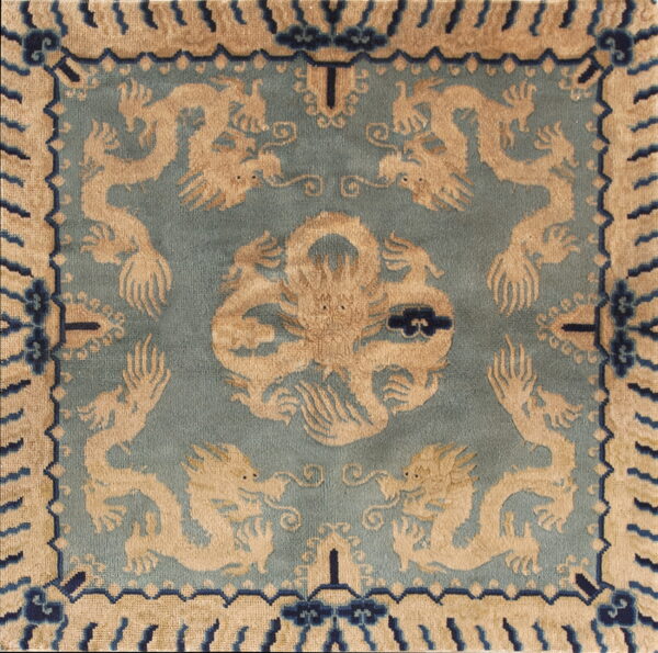 Square section of a medium-pile rug showing tan dragons on a teal field and a geometric border.