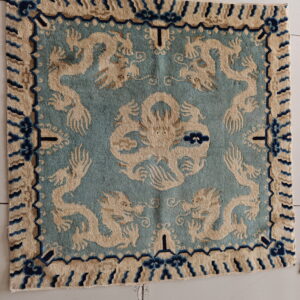 Square blue and tan rug with a low pile featuring a central and four corner dragon design.