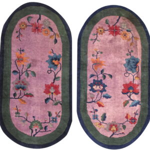 Pair of oval pink rugs featuring colorful floral vines and dual green and navy borders.