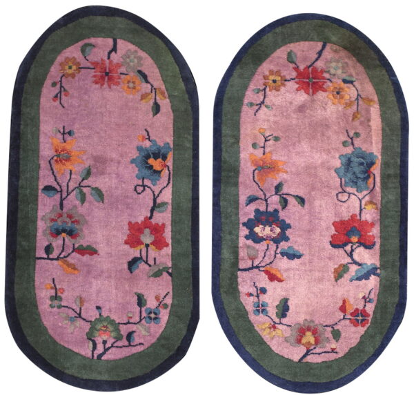 Pair of oval pink rugs featuring colorful floral vines and dual green and navy borders.
