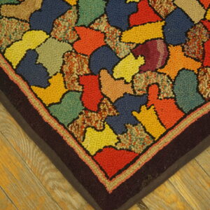 Looped pile rug with a patchwork of bright primary and secondary colors on a rustic wood floor.
