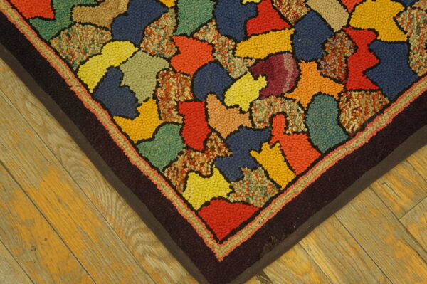 Looped pile rug with a patchwork of bright primary and secondary colors on a rustic wood floor.