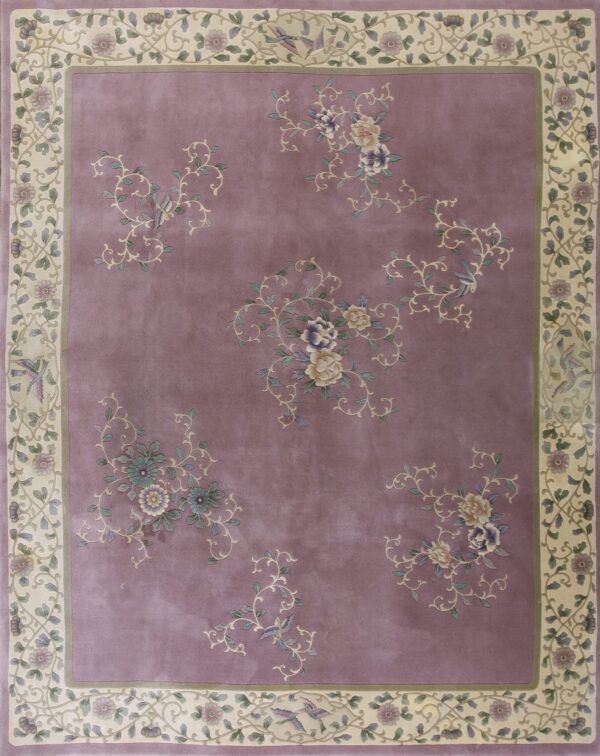 A mauve rug with a cream border featuring scrolling floral and bird patterns.
