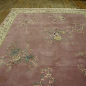 Mauve rug with scattered multicolored floral designs and a patterned cream border on distressed wooden floors.