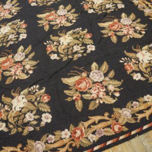 Dark navy low-pile rug with repeating bouquets of coral, cream, and gold flowers on wood flooring.
