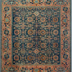 Ornate blue rug with dense floral motifs and a wide coral orange and teal border.