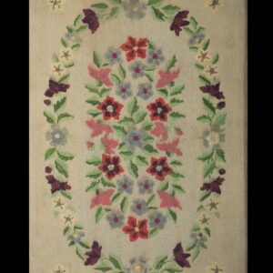 Low-pile floral rug with a central bouquet and large oval vine border on a neutral beige background.