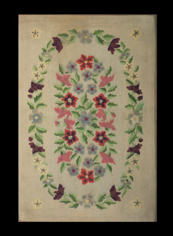 Low-pile floral rug with a central bouquet and large oval vine border on a neutral beige background.