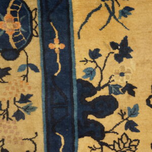 Golden yellow rug detail features thick navy borders and intricate blue, teal, and orange botanical designs.
