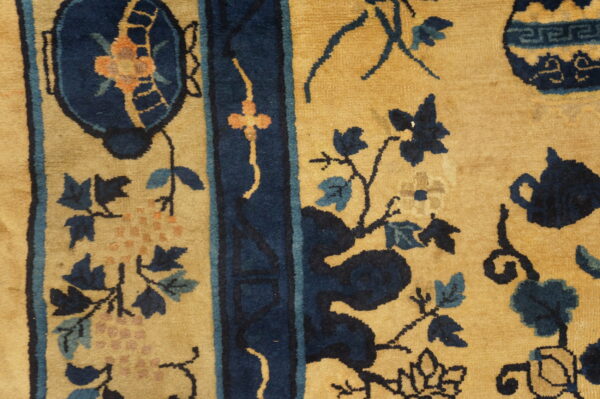Golden yellow rug detail features thick navy borders and intricate blue, teal, and orange botanical designs.