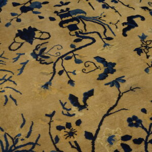 Gold rug detail with sprawling dark blue floral and vine designs and a dark border.