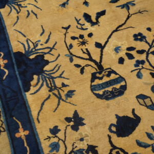 Tan field rug featuring a dark blue border and intricate botanical and object motifs.