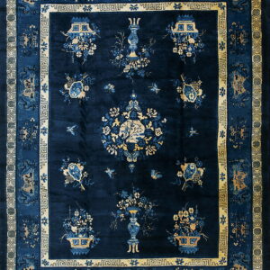 Navy blue rug featuring ornate gold borders and a field with stylized blue and tan floral and vase motifs.