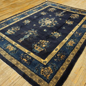 Navy blue area rug with gold and light blue botanical and geometric patterns rests on light wood planks.